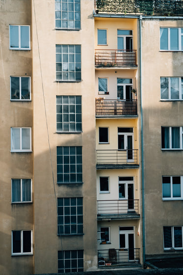 the side of a yellow buildings with balconies and windows