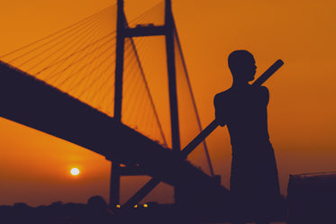 the silhouette of a man rowing against a sunset orange sky