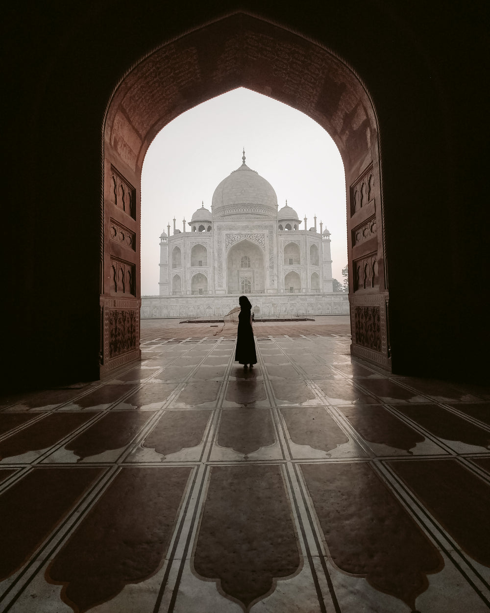 the silhouette of a person standing in a carved archway