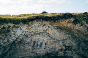 the small figure of a man walking on the hill top of a cliff