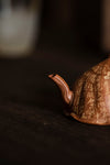 the spout of a rust colored teapot