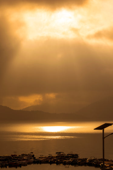 the sun drops through the clouds on the water below