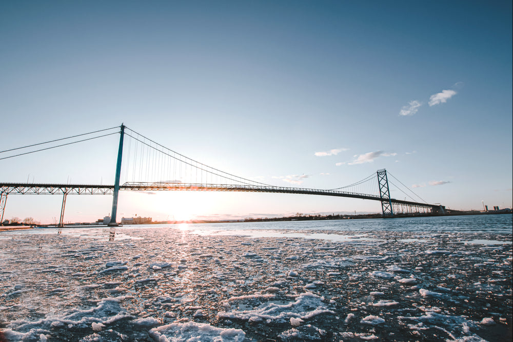 the sun sets behind a long metal bridge in winter