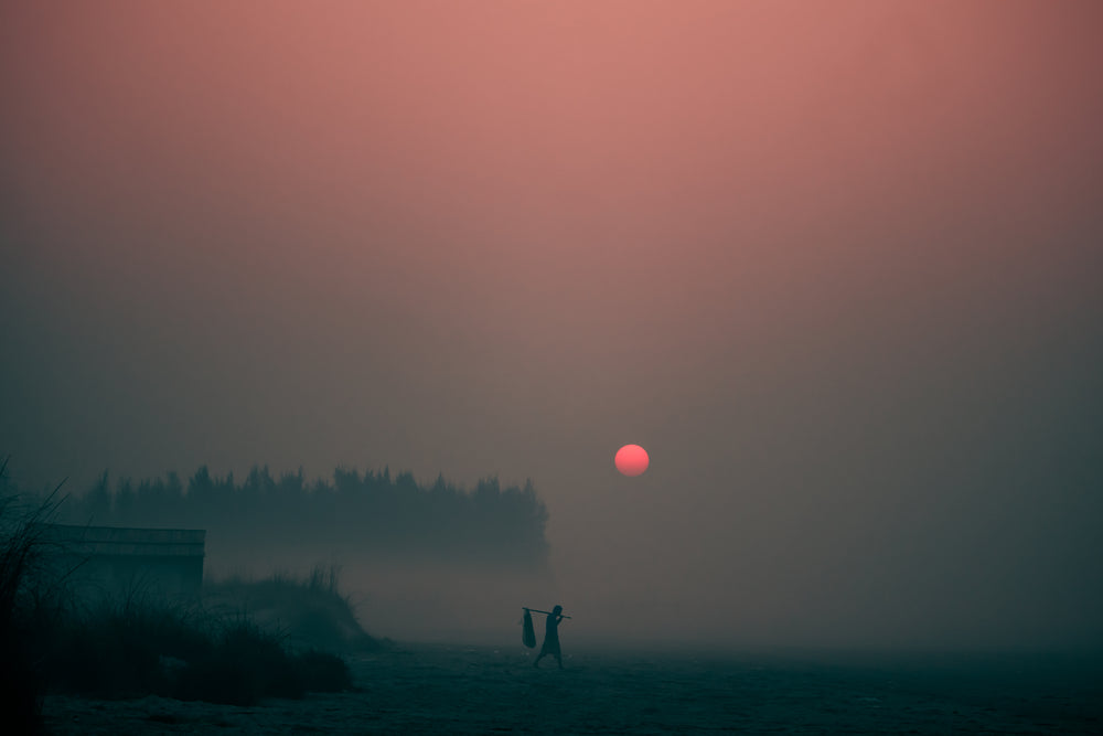 the sun sets through a thick evening fog