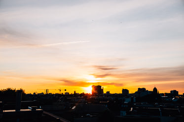 the sun setting over a silhouetted cityscape