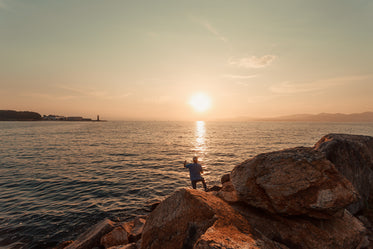 the sunsets while a fisherman casts