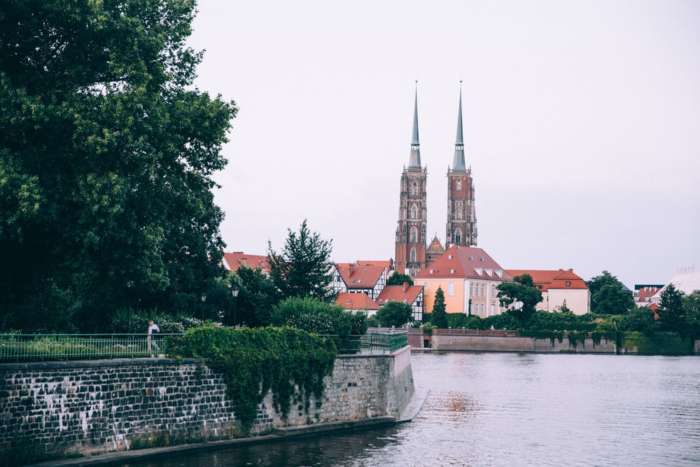 the tree-lined banks of a river reveal spires and rooftops