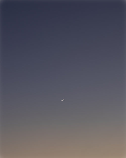 thin crescent moon in the dark blue sky