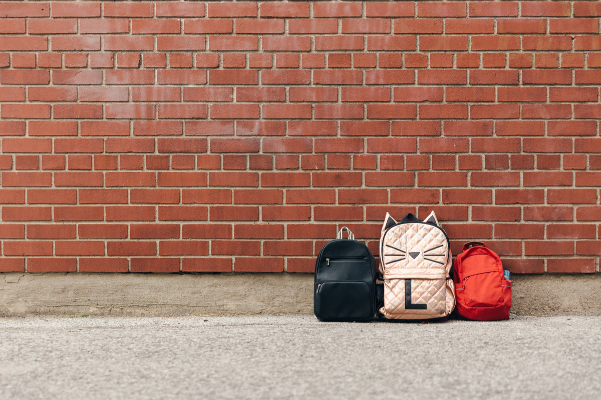 three children's backpacks brick negative space