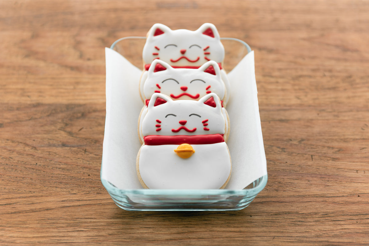 three fortune cat cookies lined in a container