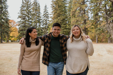 three friends pose for the camera in an open field