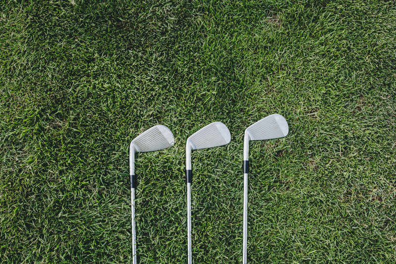 three golf clubs on green - two golf clubs on the grass