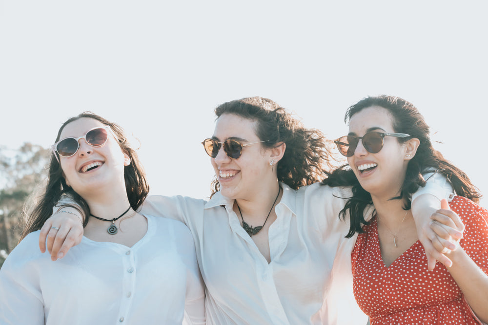 three happy people wearing sunglasses outdoors