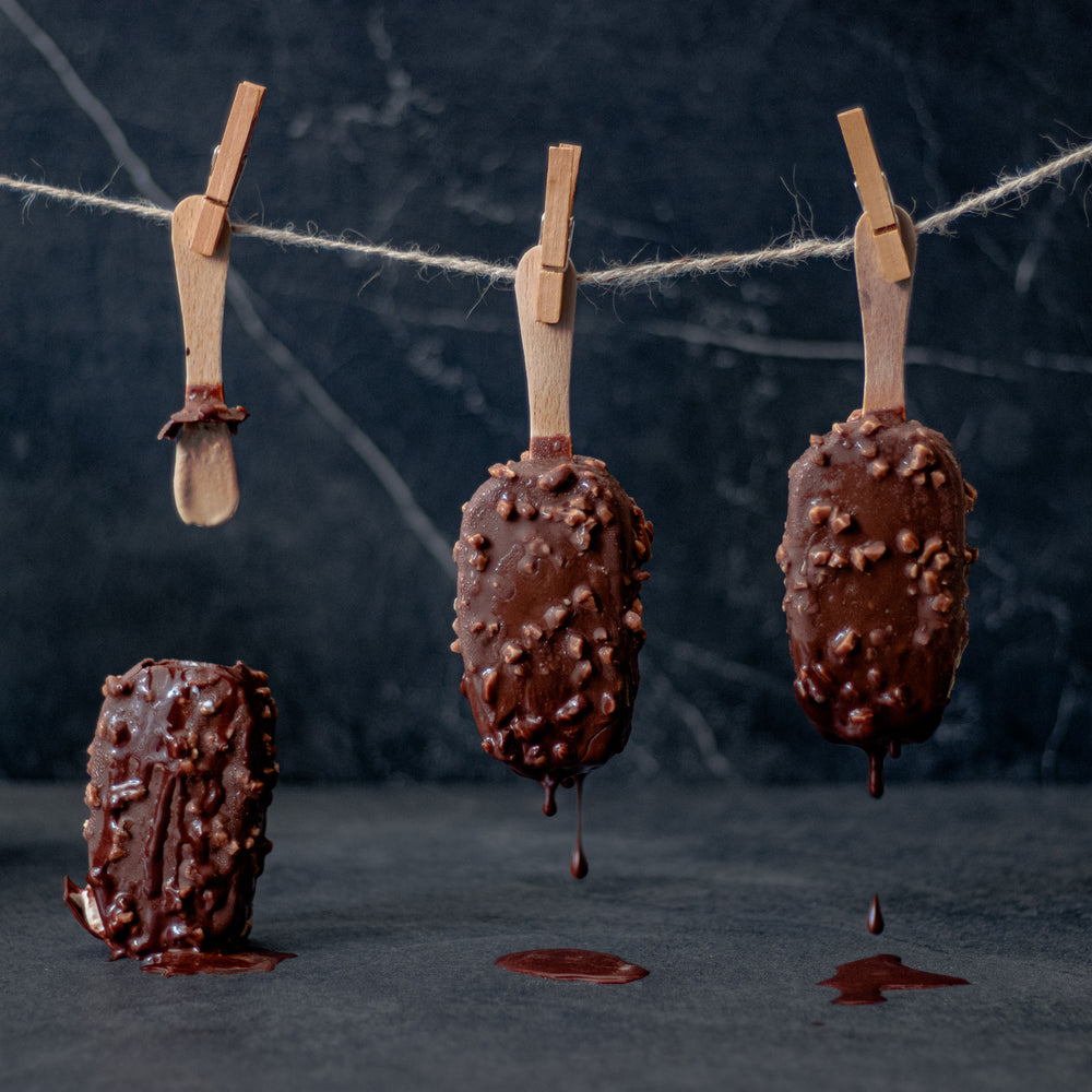 three ice cream bars hang from clothespins upside down