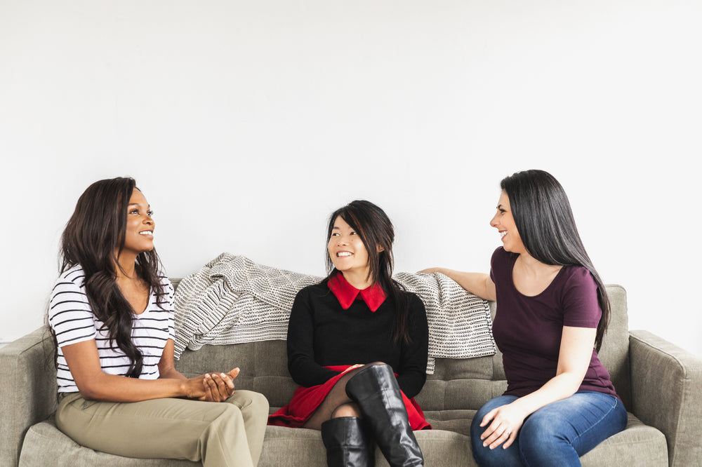 three models share a smile on a grey sofa