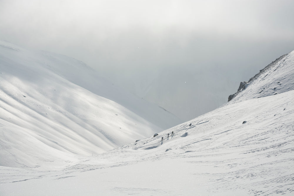 three people hiking up a snow covered mountain