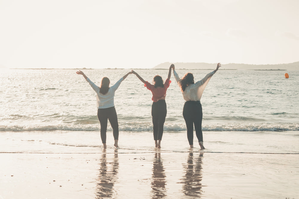 three people hold hands with their arms to the sky