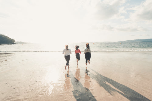 three people running towards the ocean