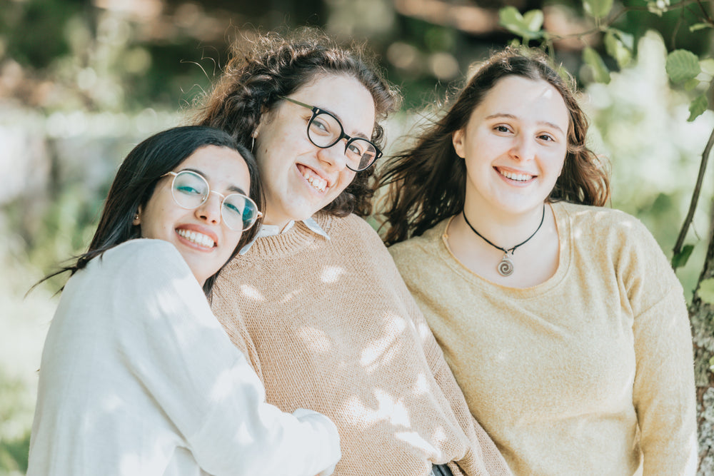 three people stand in shade and smile