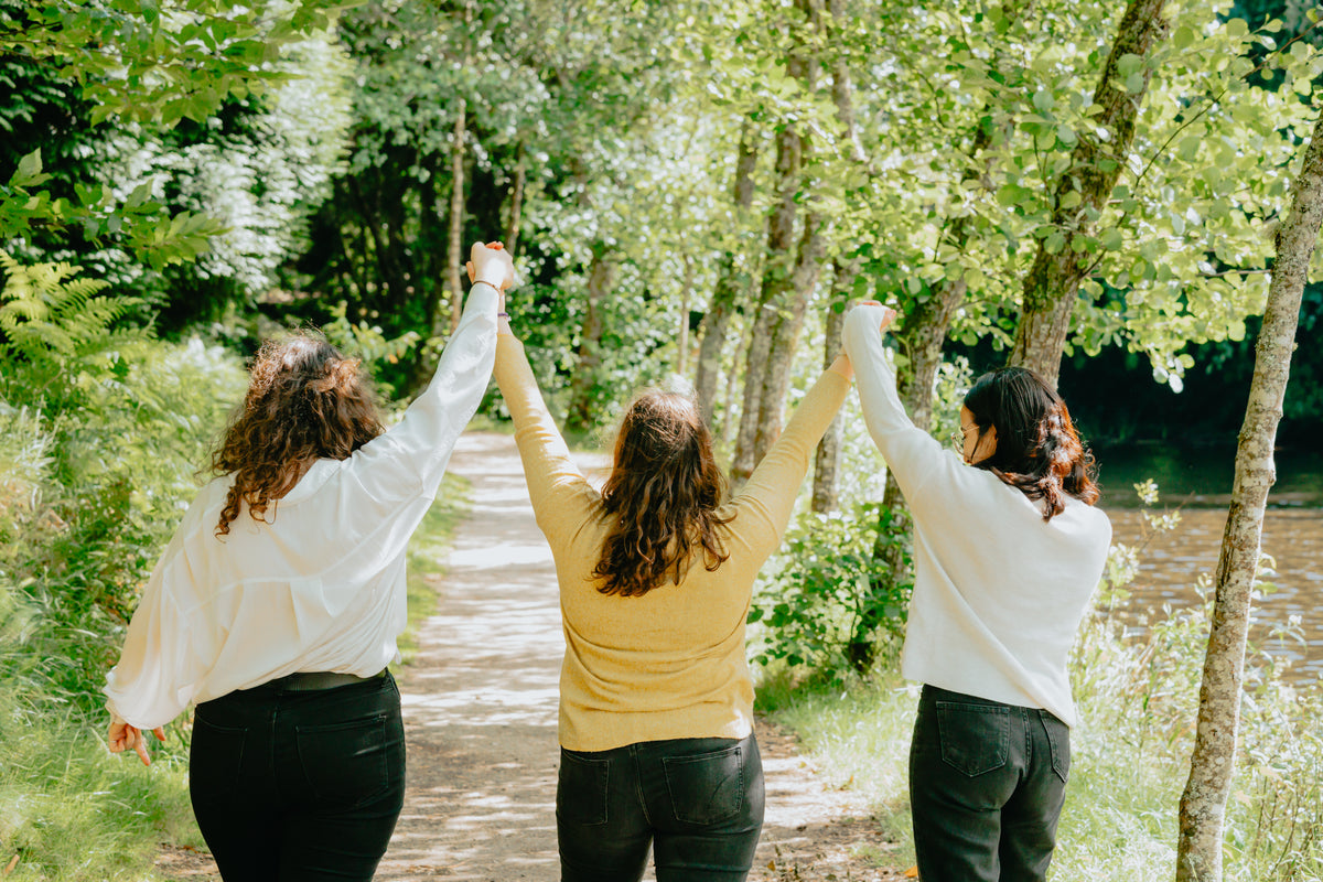 three people with their hands up on a forest trail