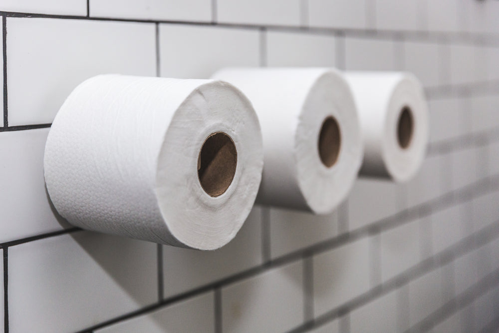three rolls of toilet paper on white tile wall