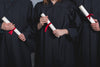 three students holding diplomas