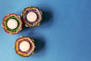 three tealights in diya on blue tabletop