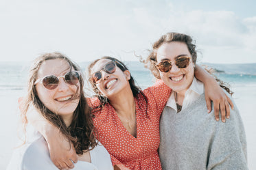 three woman in sunglasses smile wide for the camera