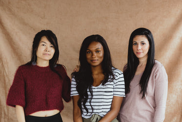mulheres de etnias diferentes posam em frente a fundo rosa