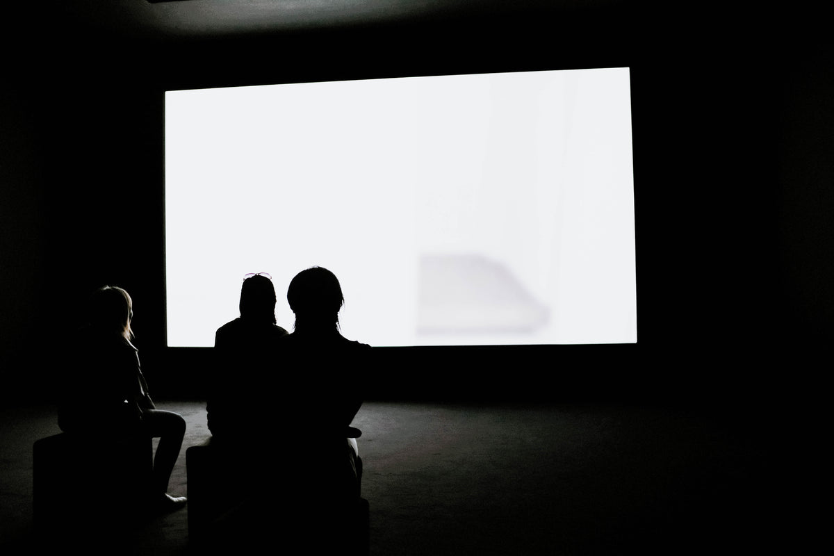 三个女人在一个黑暗的房间里看着一个发光的白色屏幕