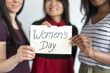 three women stand together celebrating women's day