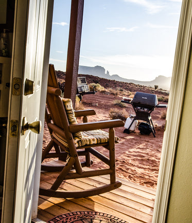 through a door a rocking chair on a porch overlooks the desert