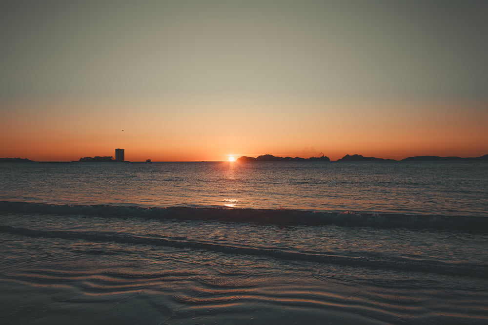 tide rolling to shore under sunset