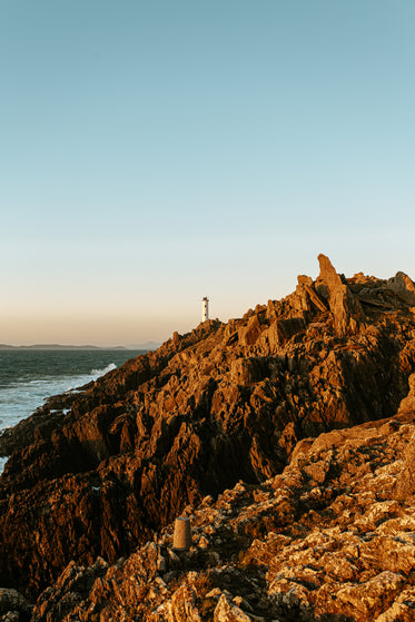 tiny lighthouse beyond rocky shore