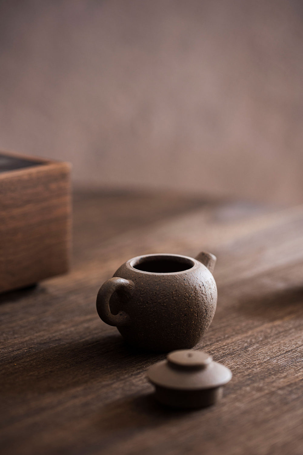 tiny teapot sits with the lid off on a wooden table