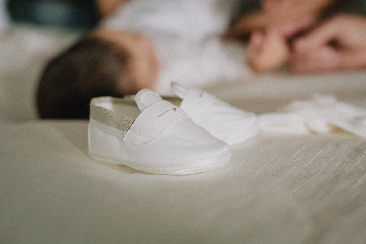 tiny white baby shoes on white sheet