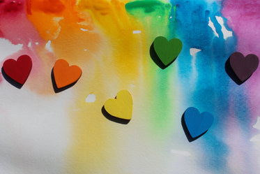 tiny wooden rainbow hearts on watercolour painted background