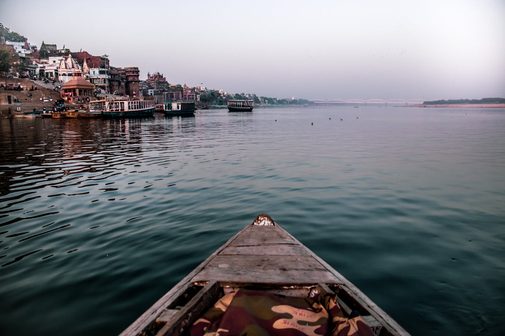 tip of a boat on blue water with a town nearby