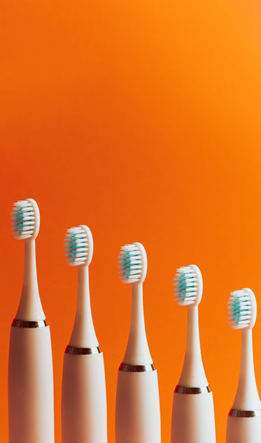 toothbrushes lined up in a row against orange