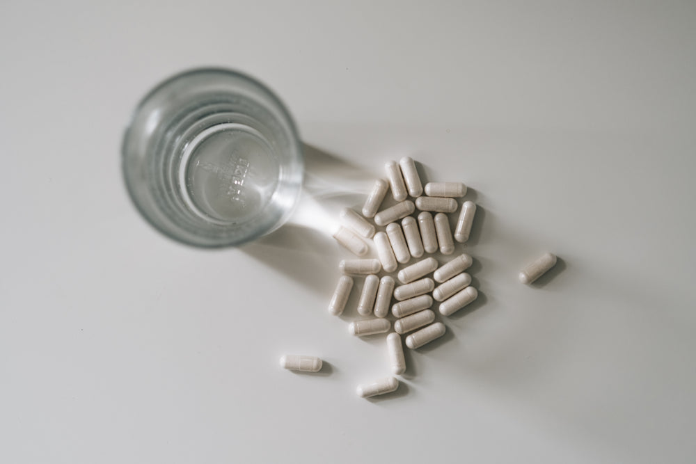 top view of a glass of water and pills on white table