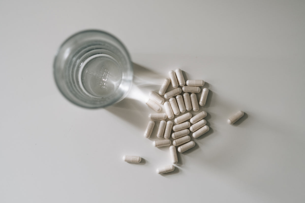 top view of a glass of water and pills on white table