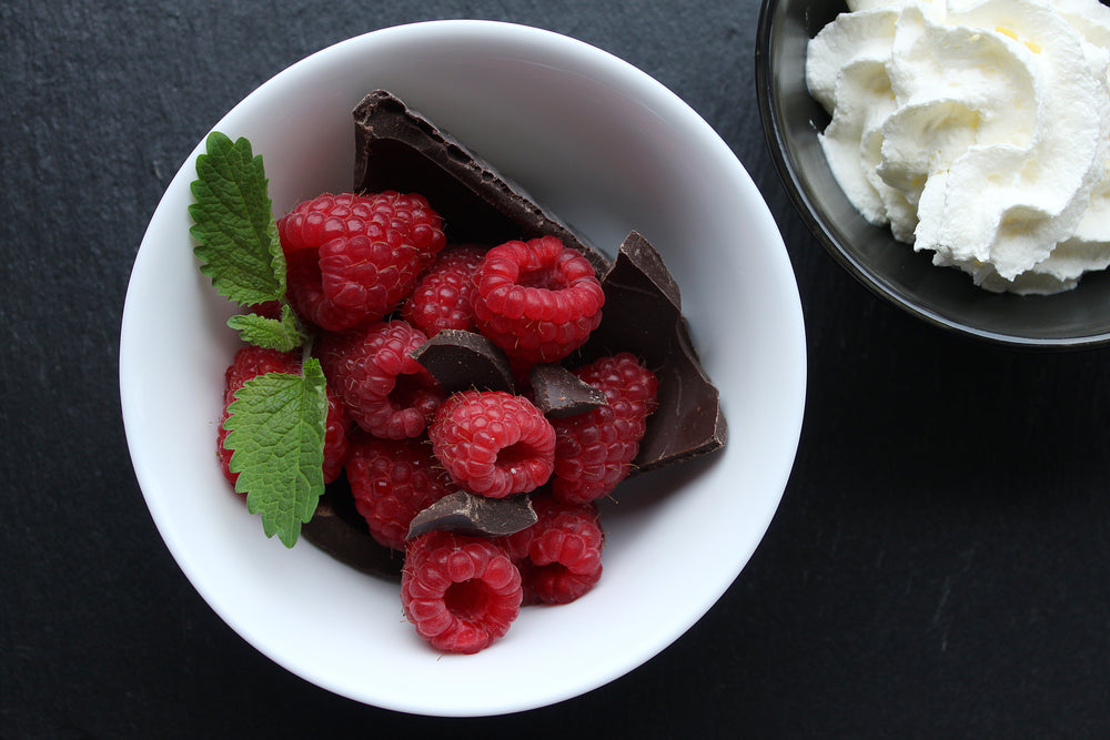top view of raspberries chocolate and mint in white dish