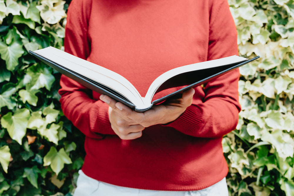 torso of a person in a red sweater holding open a book
