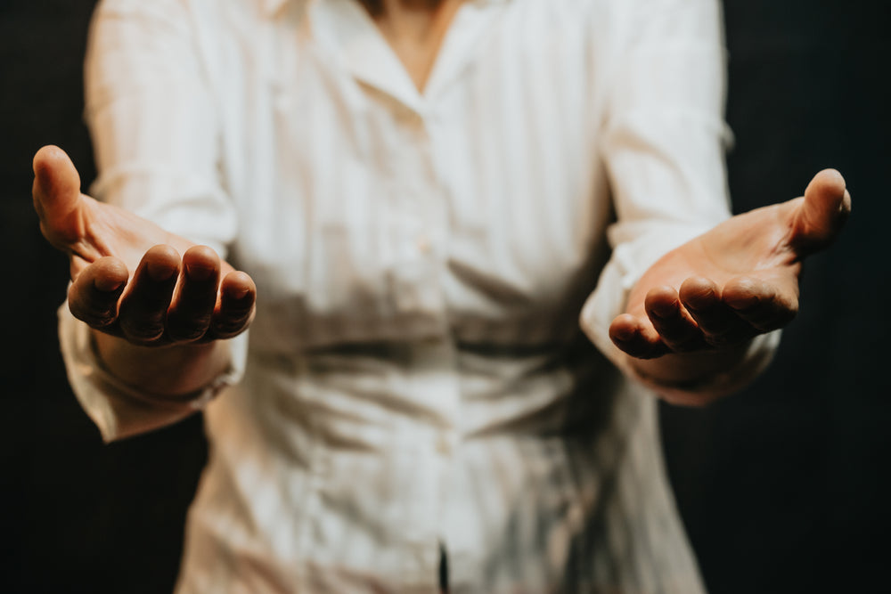 torso of a person in white holding their palms up