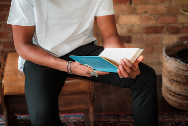 torso of a person in white shirt reading a novel