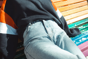 torso of a person sitting on a rainbow painted bench