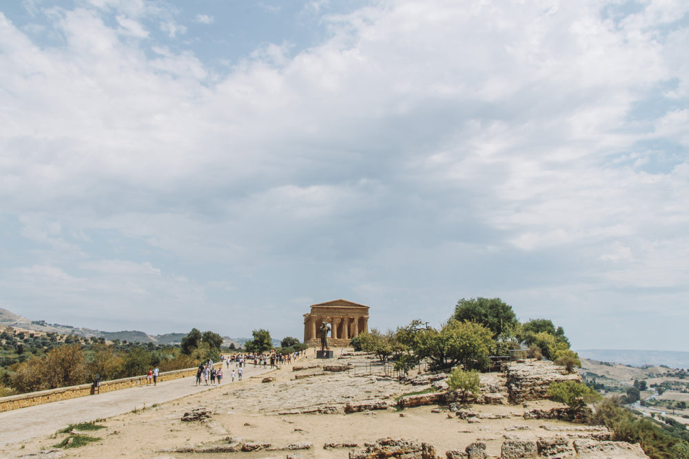 travelers walk past a temple on the coast