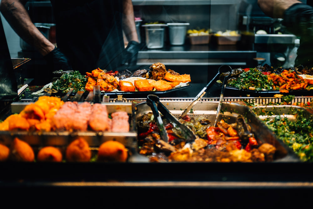 trays of colorful food with tongs