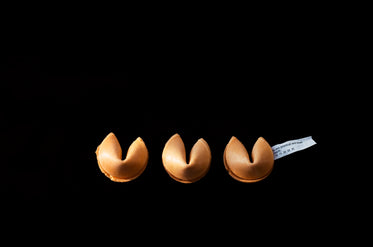 trio of fortune cookies sit unbroken on black background