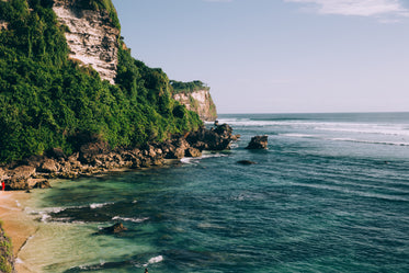 turquoise blue ocean waters along jungle covered cliffside